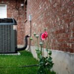 qtq80-aMImuS A red flower in front of an air conditioner.