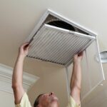qtq80-kF1jku A man is holding an air filter up to the ceiling.